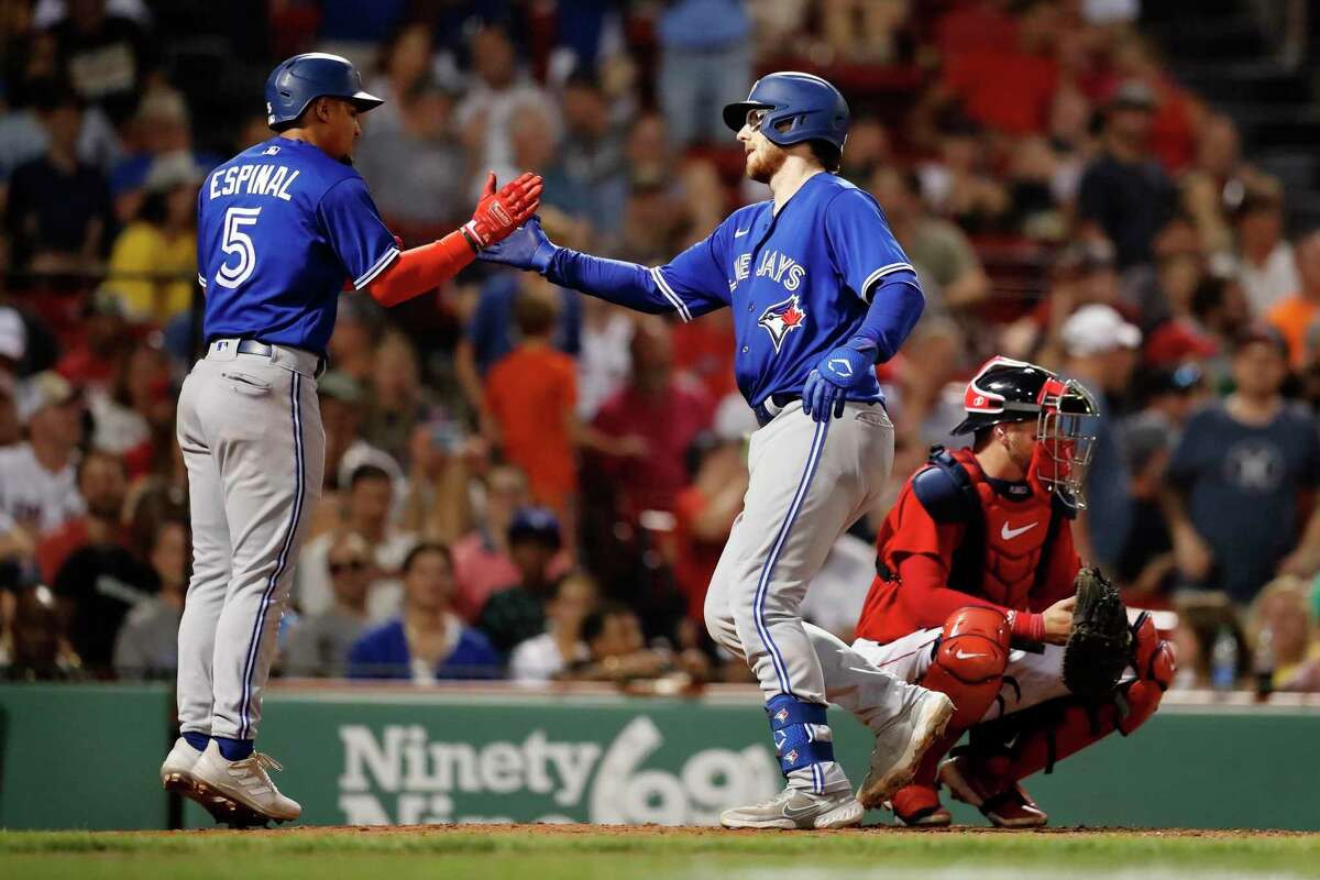 Toronto Blue Jays' Danny Jansen, center, celebrates after driving in Santiago Espinal, left, with a home run against the Boston Red Sox during the sixth inning of a baseball game Friday, July 22, 2022, in Boston. (AP Photo/Michael Dwyer)