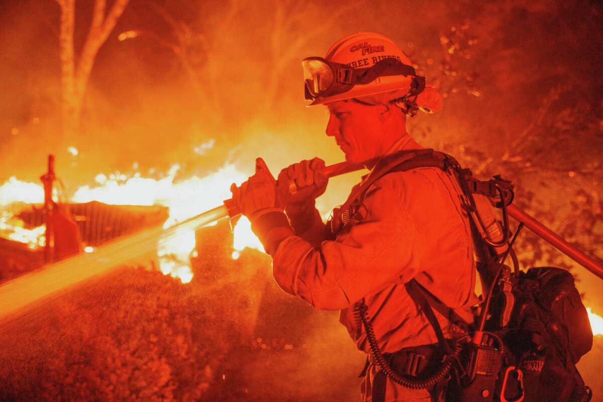 Firefighter Justin Montgomery defends a home on Triangle Road as the Oak Fire burns in unincorporated Mariposa County.