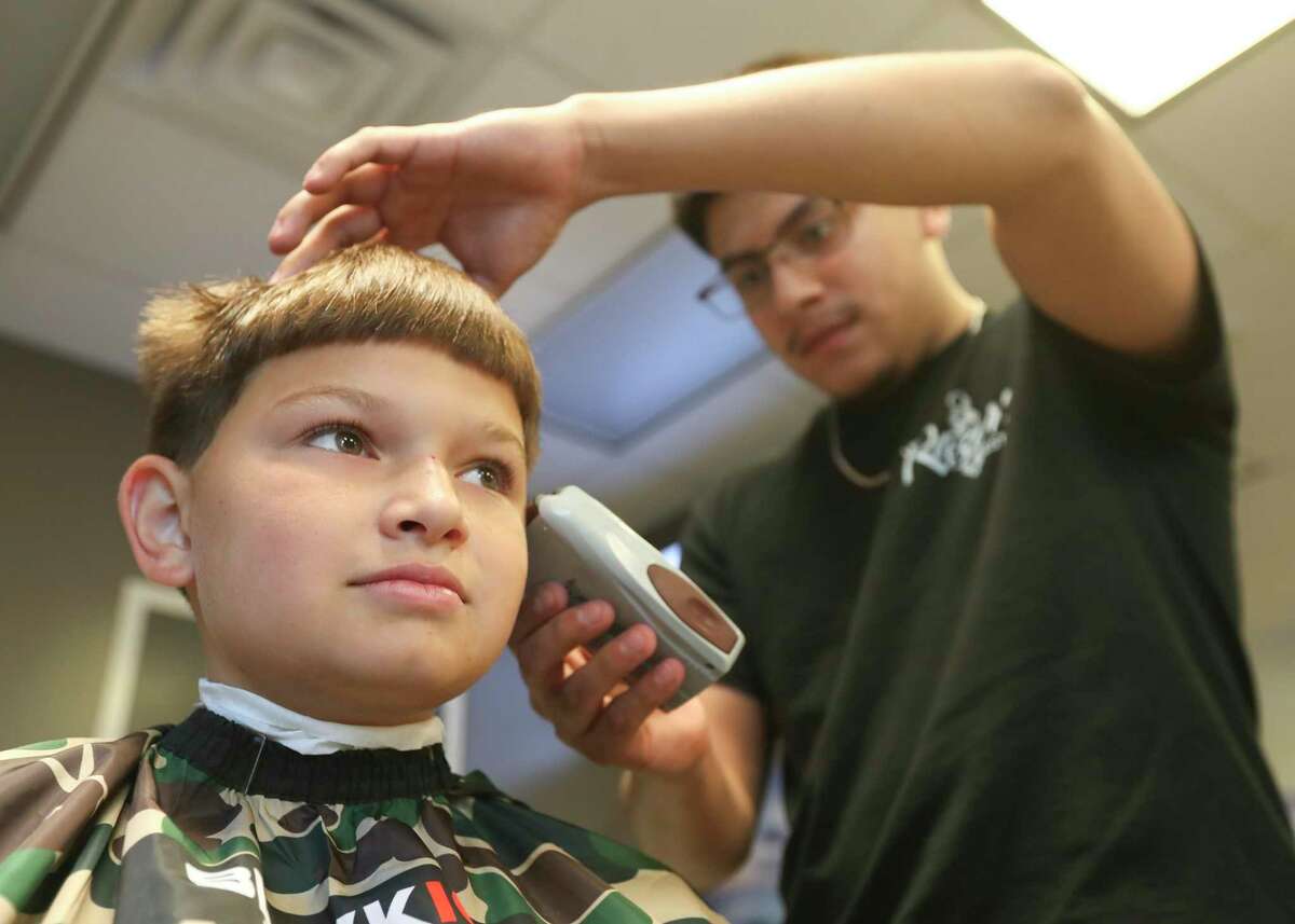 Jayden Estrada, left, gets high hair cut by Randy Hernandez during Lone Star Family Health Center’s annual Don’t Miss The Bus event, Saturday, July 23, 2022, in Conroe. The event focused on various bath-to-school health services such as eye screenings, immunizations, community outreach organizations.