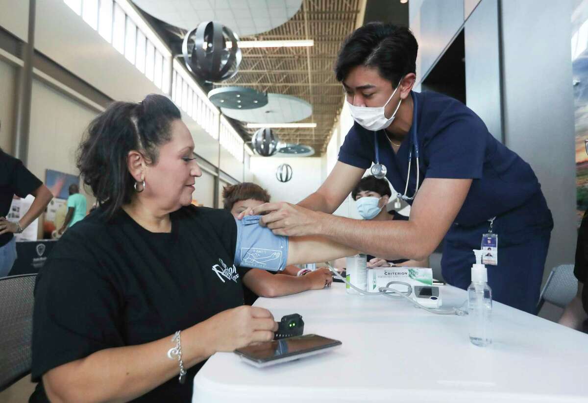 Connie Estrada, left, has her blood pressure taken by Sam Houston State University medical student Justin Varias during Lone Star Family Health Center’s annual Don’t Miss The Bus event, Saturday, July 23, 2022, in Conroe. The event focused on various bath-to-school health services such as eye screenings, immunizations, community outreach organizations.
