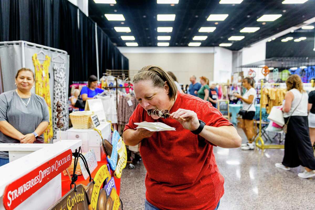 A shopper takes a bite of her chocolate dip strawberries from Hour Reasons during the Small Business Expo at the Pasadena Convention Center, Saturday, July 23, 2022, in Pasadena.