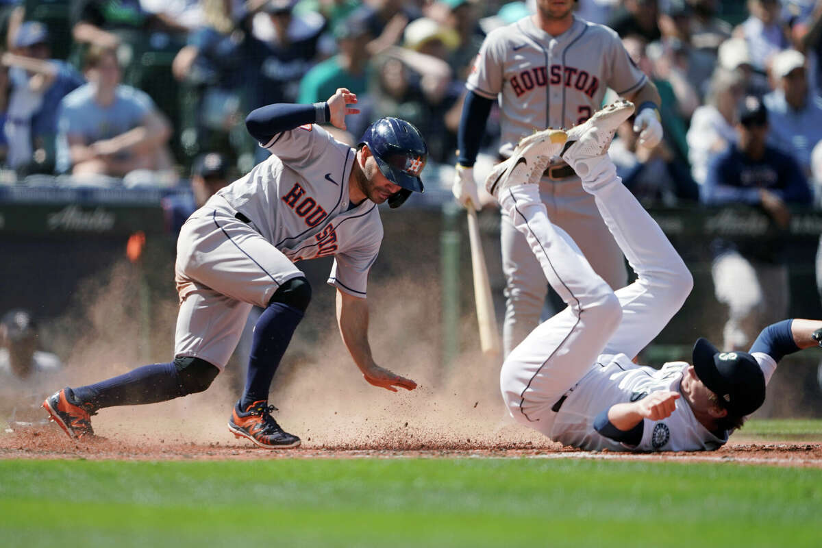 Houston Astros' Jose Altuve, left, is safe at home, scoring on a wild pitch by Seattle Mariners' Ryan Borucki, right, during the eighth inning of a baseball game Saturday, July 23, 2022, in Seattle. (AP Photo/Ted S. Warren)