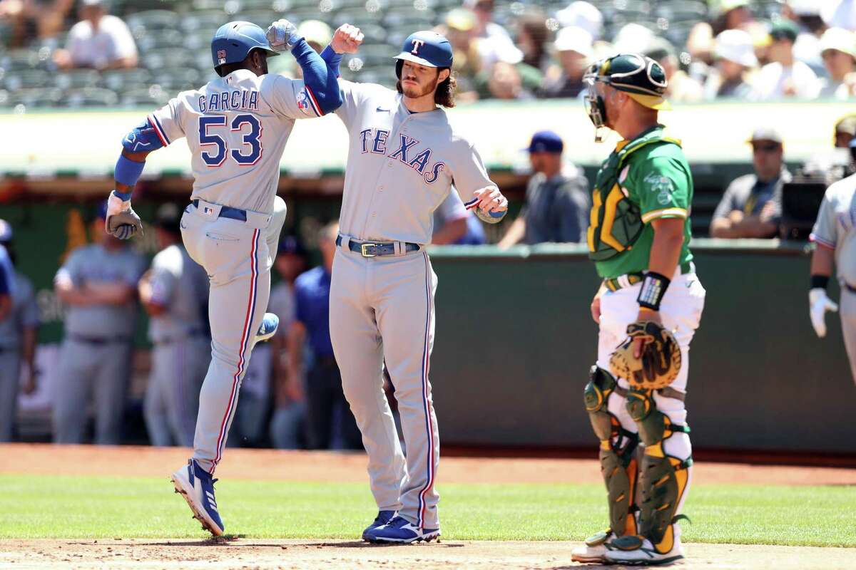 Oakland Athletics’ Stephen Vogt watches as Texas Rangers’ Adolis Garcia celebrates his 2-run home run with Jonah Heim in 1st inning during MLB game at Oakland Coliseum in Oakland, Calif., on Sunday, July 24, 2022.