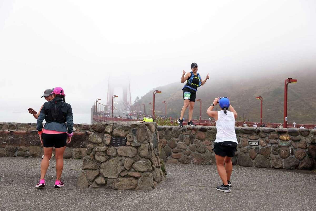 Tine Maria Caballero pauses from running to be photographed with the Golden Gate Bridge at North Vista Point during the San Francisco Marathon.