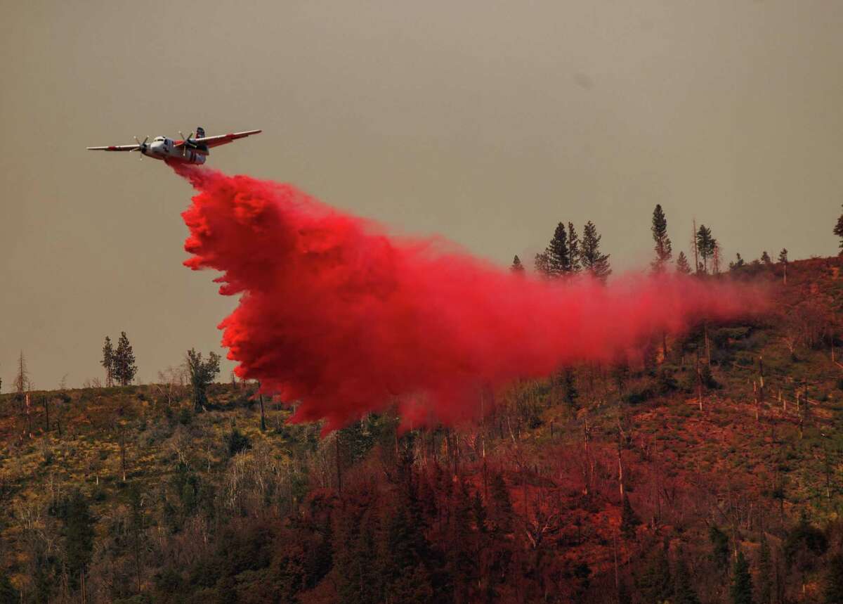 在加利福尼亚州马里波萨县，一架飞机在橡树大火上投放阻燃剂。