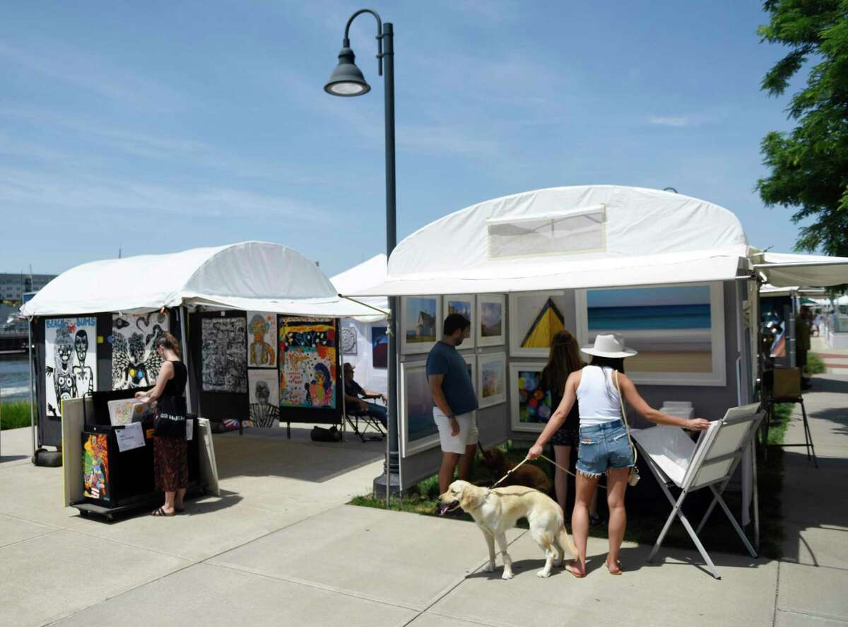People view artwork for sale at the Stamford Arts Festival at Harbor Point in Stamford, Connecticut, Sunday, July 24, 2022. The seventh annual juried exhibition showcased one-of-a-kind works in a variety of mediums, including painting, sculpture, metalwork, . printing, jewelry, etc.  The event included demonstrations, hands-on art projects and children's activities.