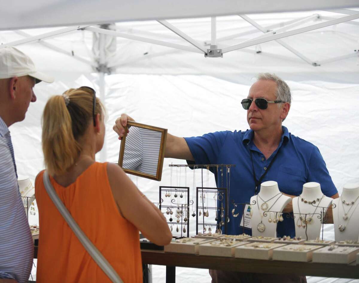 Weston artist Mikhail Zahalov shows his jewelry to buyers at the Stamford Arts Festival at Harbor Point in Stamford, Connecticut, Sunday, July 24, 2022. The seventh annual juried exhibition showcased one-of-a-kind works in a variety of mediums, including painting, sculpture, metalwork , printing, jewelry, etc. The event included demonstrations, hands-on art projects and children's activities.