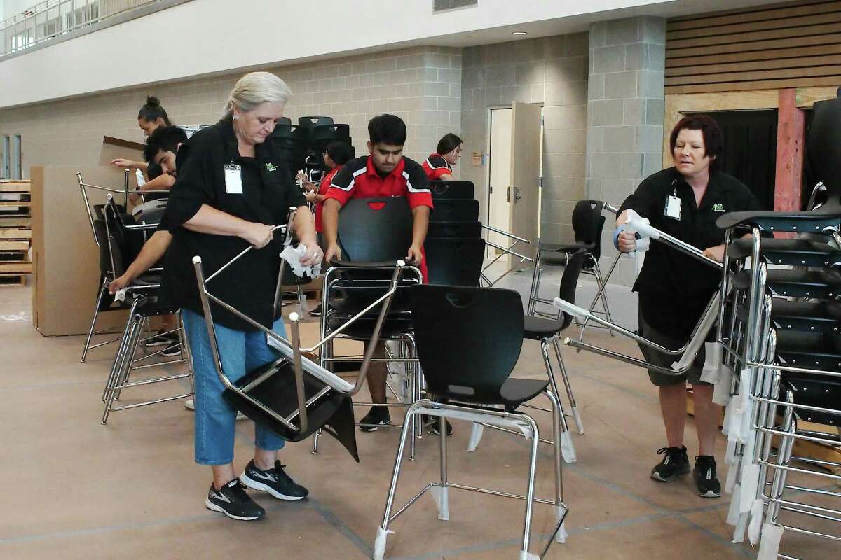 Alvin ISD’s director of purchasing and central distribution, Mickie Dietrich, left, works with Joe Martinez and Kricket Jandl to unwrap and stack chairs to be transported to classrooms at the new Iowa Colony High School before school opens in August.