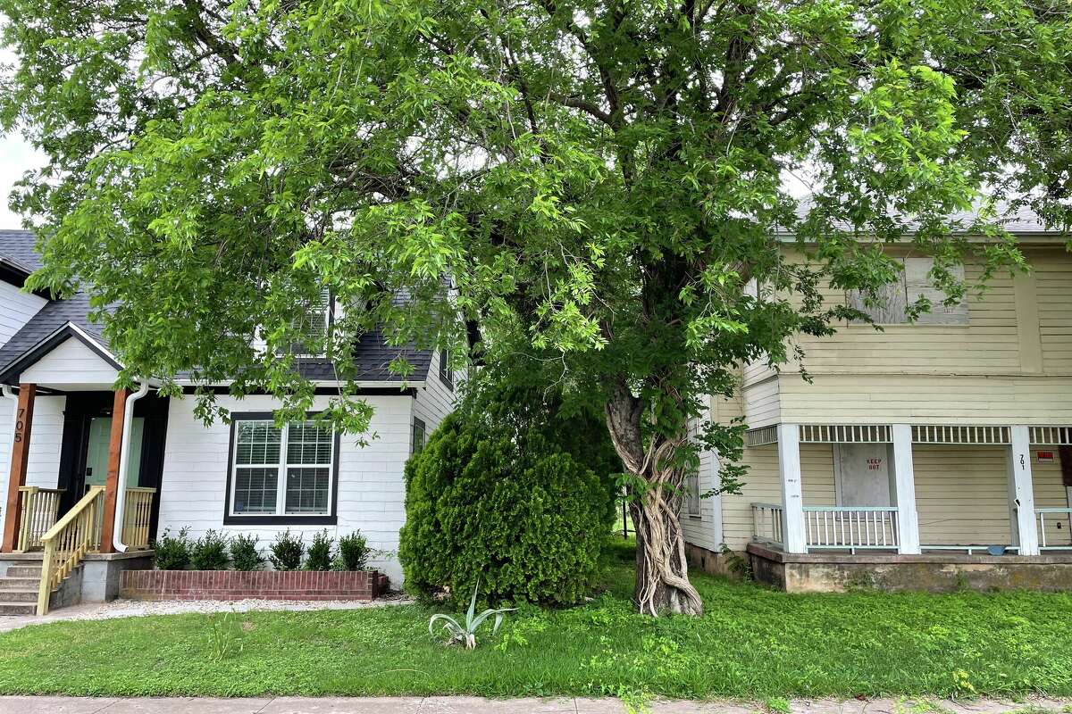 Two houses in downtown Waco: one boarded up with 'KEEP OUT' on it, the other currently rents for $303 a night on AirBnB.