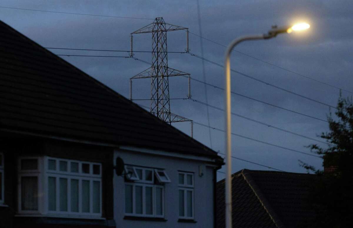 An electricity transmission tower near an illuminated street lamp in Upminster, UK, on Monday, July 4, 2022. The UK is set to water down one of its key climate change policies as it battles soaring energy prices that have contributed to a cost-of-living crisis for millions of consumers. Photographer: Chris Ratcliffe/Bloomberg