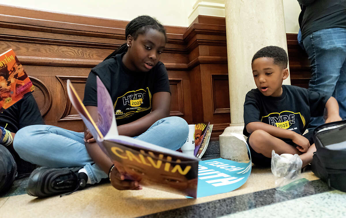 Hype Freedom School students Hailee Brown, 15, center, reads with Treyson Hall, 7, of Houston, during the Texas Freedom Network read-in demonstration on Tuesday, July 26, 2022, in Austin, Texas. Attendees read from some of the books being targeted for banning during a Texas Freedom Network’s Teach the Truth Coalition read-in demonstration held at the Texas State Capitol Rotunda.