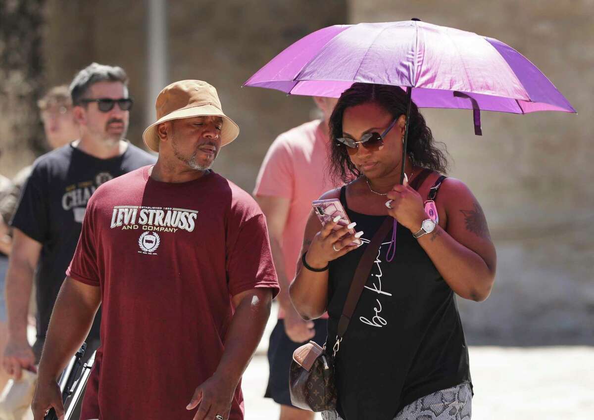 DeShayla Solomon of Texarkana use an umbrella for shade as she and her husband, Freddie, visit the Alamo on Monday.