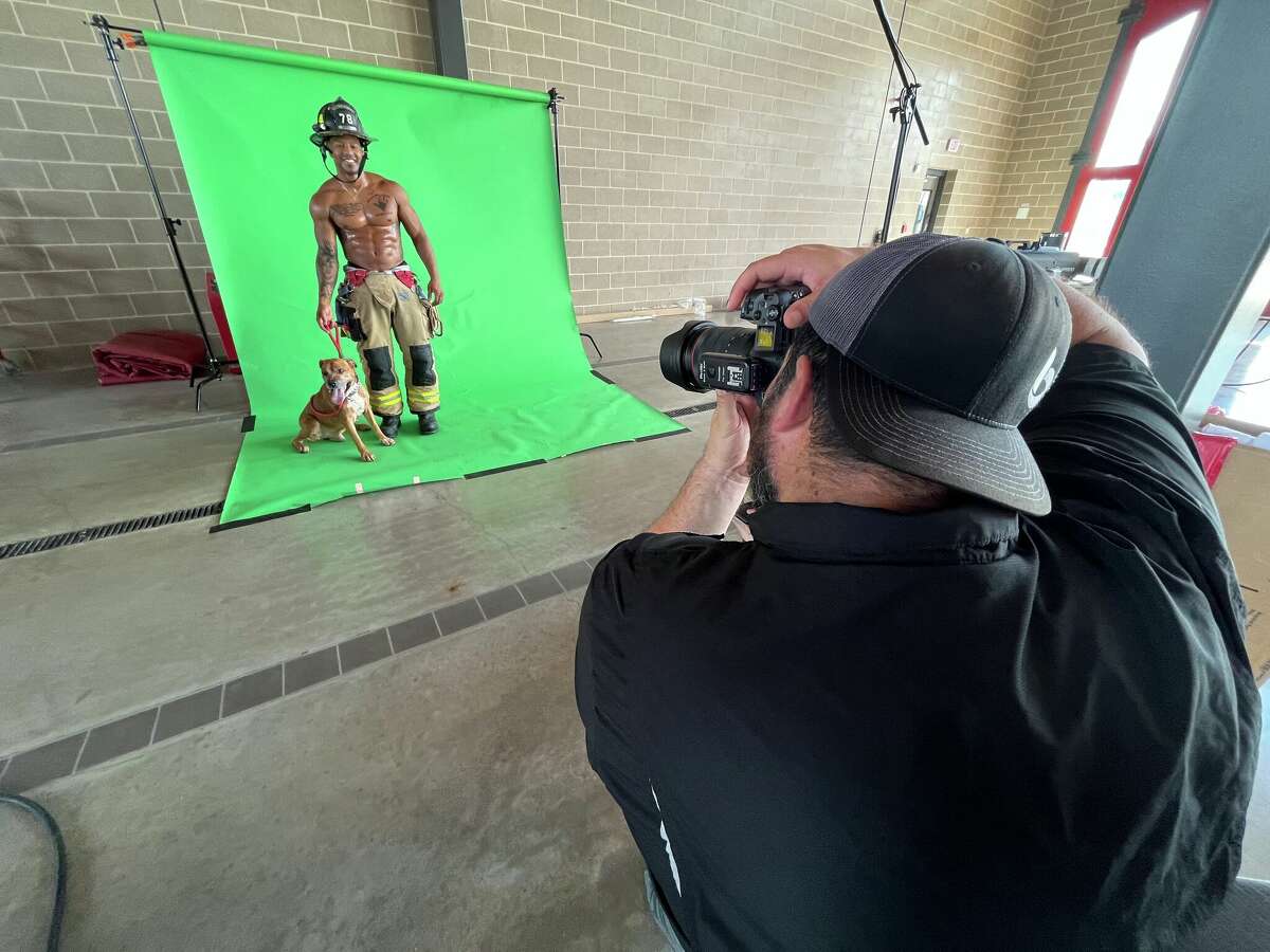 Spring Firefighter Steffon Marsh and a shelter dog are photographed in front of a green screen by photographer Robert Harrington of Bella Media during a photo shoot for the department's 2023 calendar on Tuesday, July 19, 2022.