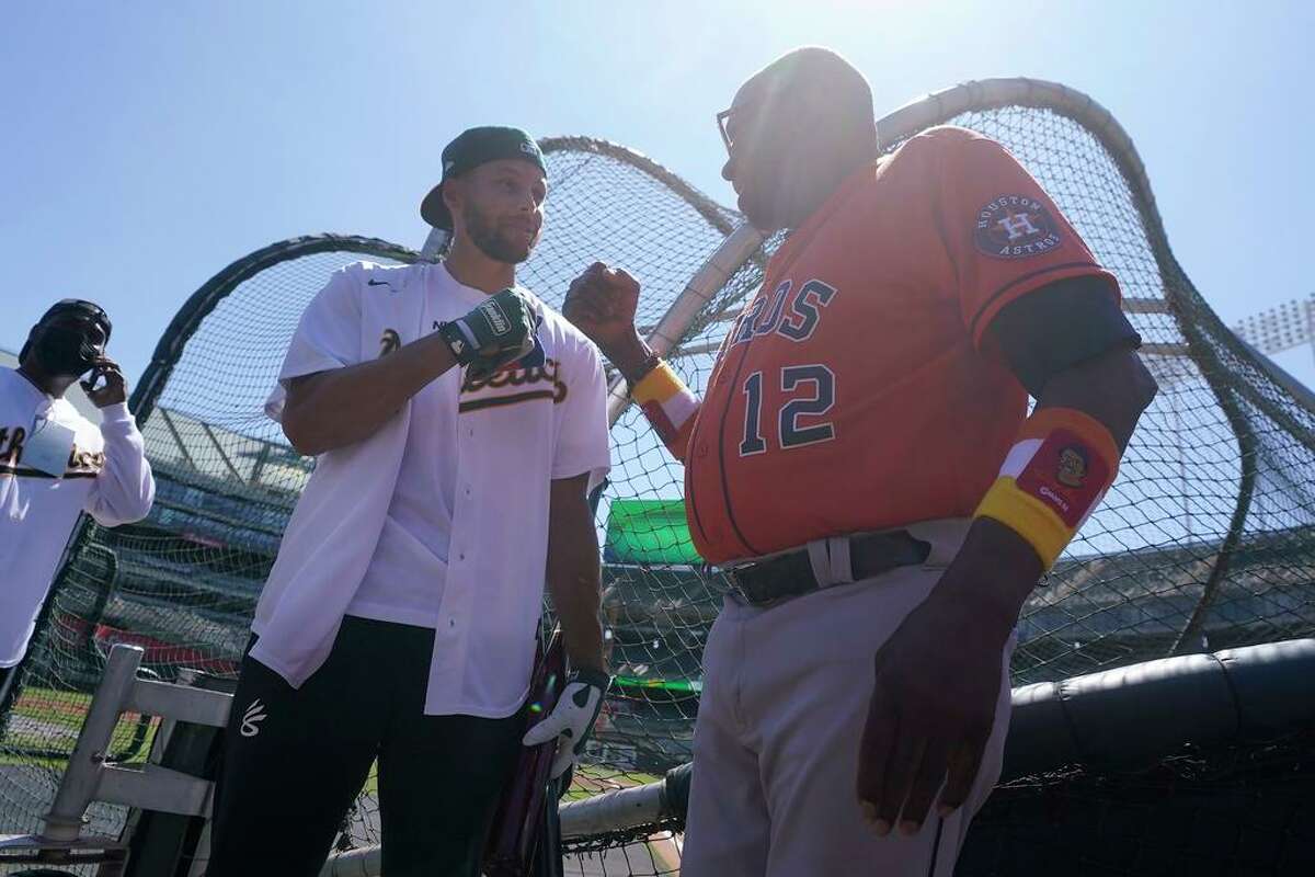 Golden State Warriors basketball player Stephen Curry, left, greets Houston Astros manager Dusty Baker Jr. after Curry took batting practice before a baseball game between the Oakland Athletics and the Astros in Oakland, Calif., Wednesday, July 27, 2022. (AP Photo/Jeff Chiu)