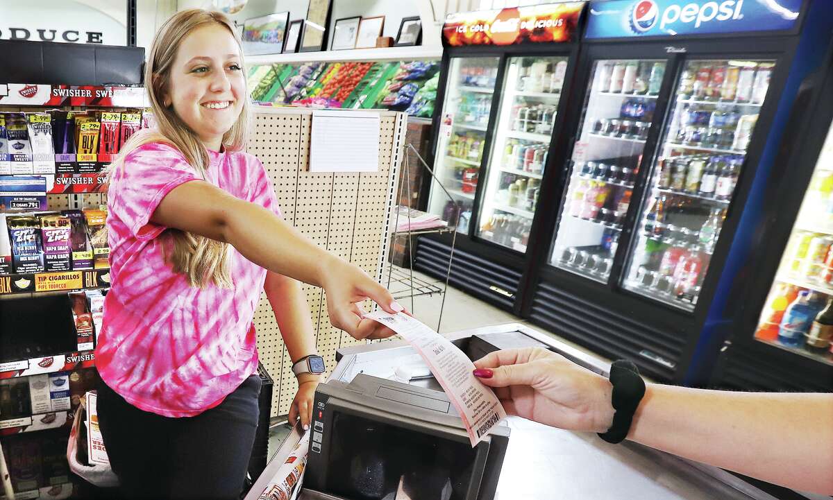 John Badman|The Telegraph Sydney Ehrman, a cashier at Schwegel's grocery store at 901 Alby St. in Alton, hands a Mega Millions lottery ticket to a purchaser on Wednesday. Only one winning ticket was sold, in suburban Chicago, for Friday's $1.28 billion jackpot. 