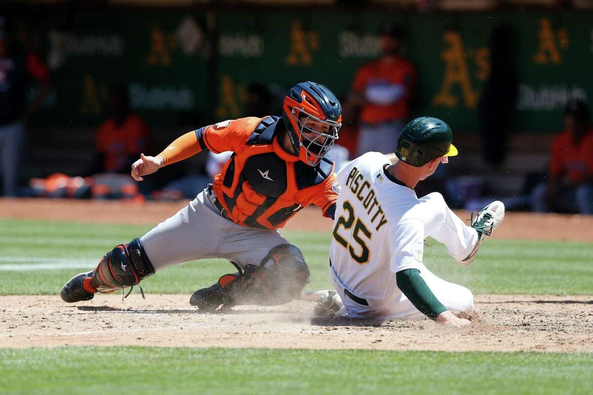 OAKLAND, CALIFORNIA - JULY 27: Stephen Piscotty #25 of the Oakland Athletics slides in safe at home plate ahead of the tag by catcher Korey Lee #38 of the Houston Astros to score on a single by Skye Bolt #11 of the Oakland Athletics in the bottom of the seventh inning at RingCentral Coliseum on July 27, 2022 in Oakland, California. (Photo by Lachlan Cunningham/Getty Images)