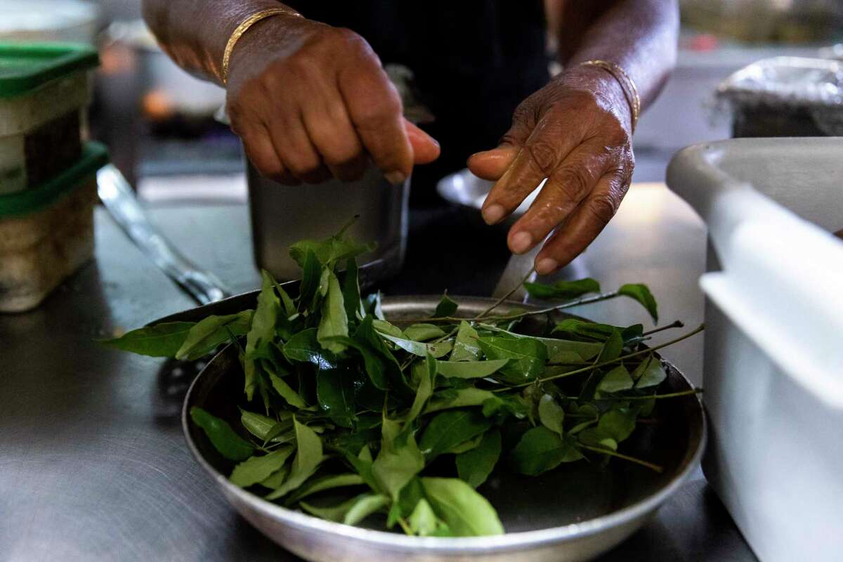 Radhamma Chinnala pulls curry leaves off the stem before seasoning the masala for dosas in the kitchen at Vik’s Chaat in Berkeley.