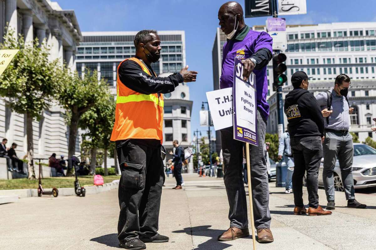 2022年7月27日星期三，在旧金山市政厅外的罢工期间，罗伯特·d·克罗克特(左)与Tenderloin住房诊所的同事伊曼纽尔·怀特聊天。