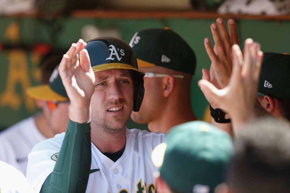 OAKLAND, CALIFORNIA - JULY 27: Stephen Piscotty #25 of the Oakland Athletics celebrates in the dugout after scoring on a single by Skye Bolt #11 in the bottom of the seventh inning against the Houston Astros at RingCentral Coliseum on July 27, 2022 in Oakland, California.
