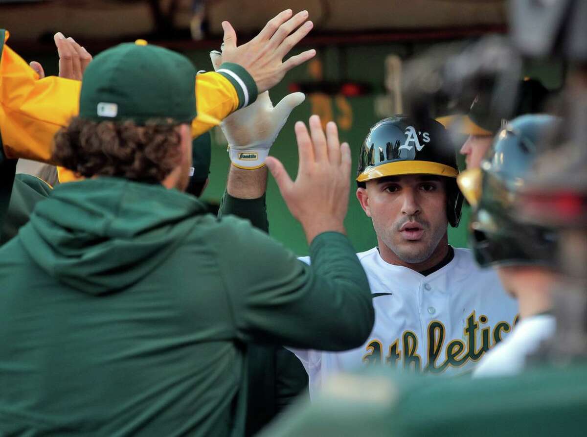 Ramon Laureano (22) high fives teammates after scoring on a single by Elvis Anbdrus (17) in the fourth inning as the Oakland Athletics played the Houston Astros at the Coliseum in Oakland, Calif., on Monday, July 25, 2022.