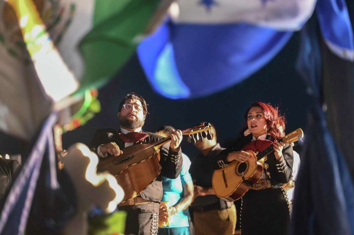 Members of Mariachi Azul play before a shrine representing the 53 migrants from Mexico, Honduras and Guatemala who died in a trailer on Quintana Road on June 27. Hundreds of people gathered on the spot on July 27, 2022.