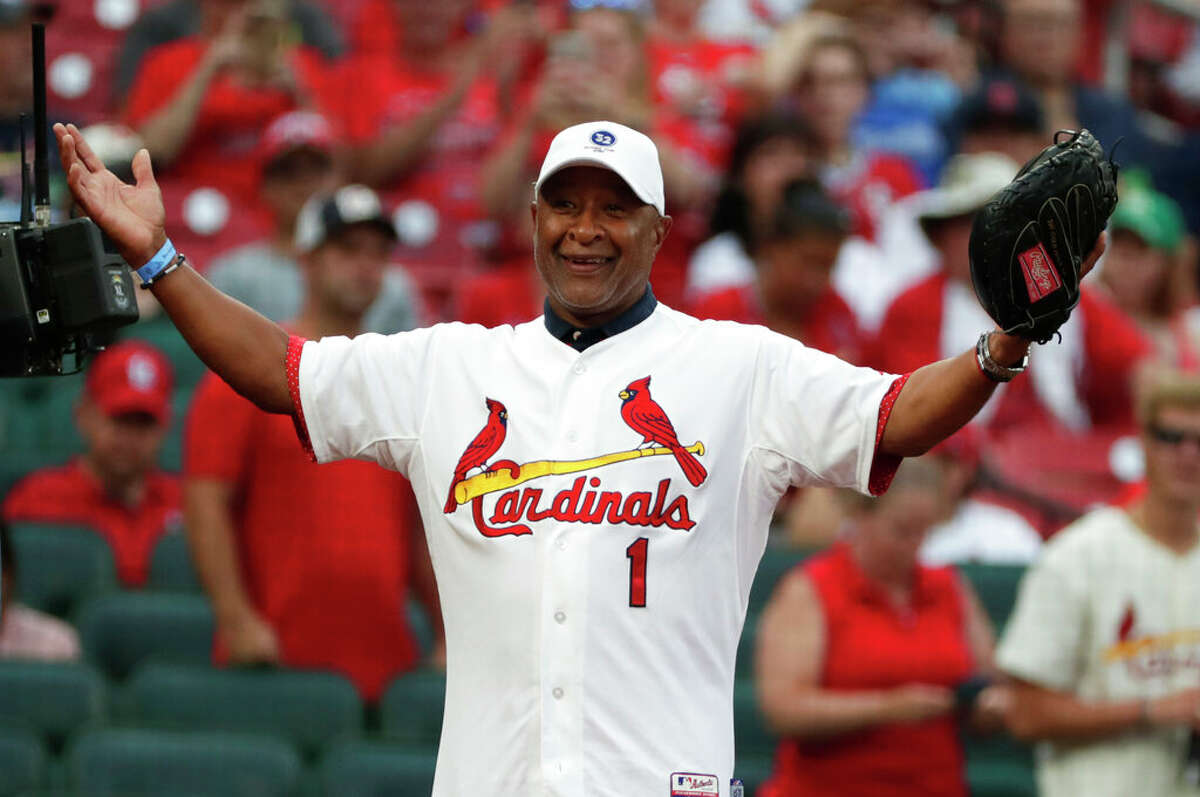 St. Louis Cardinals Hall-of-Famer Ozzie Smith gestures to his longtime friend and teammate, assistant coach Willie McGee, on the Cardinals bench before a baseball game between the Cardinals and the Kansas City Royals, Friday, Aug. 6, 2021, in St. Louis. 