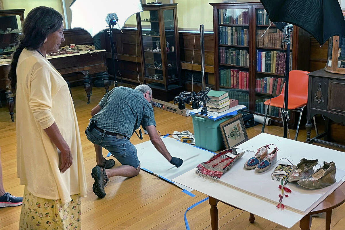 Leola One Feather (left), of the Oglala Sioux Tribe in South Dakota, watches July 19 as John Willis photographs Native American artifacts at the Founders Museum in Barre, Massachusetts. The private museum, which is housed in the town library, is working to repatriate as many as 200 items believed to have been taken from Native Americans massacred by U.S. soldiers in 1890 at Wounded Knee Creek. Willis is photographing the items for documentation, ahead of their expected return to the tribe.