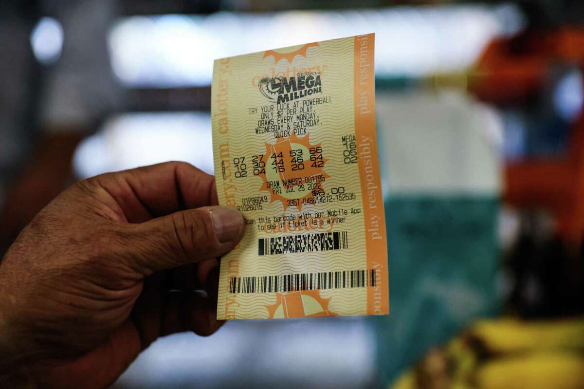 A customer holds up his Mega Millions lotto ticket he purchased at W&K Market in San Francisco, Calif., on Wednesday, July 27, 2022.