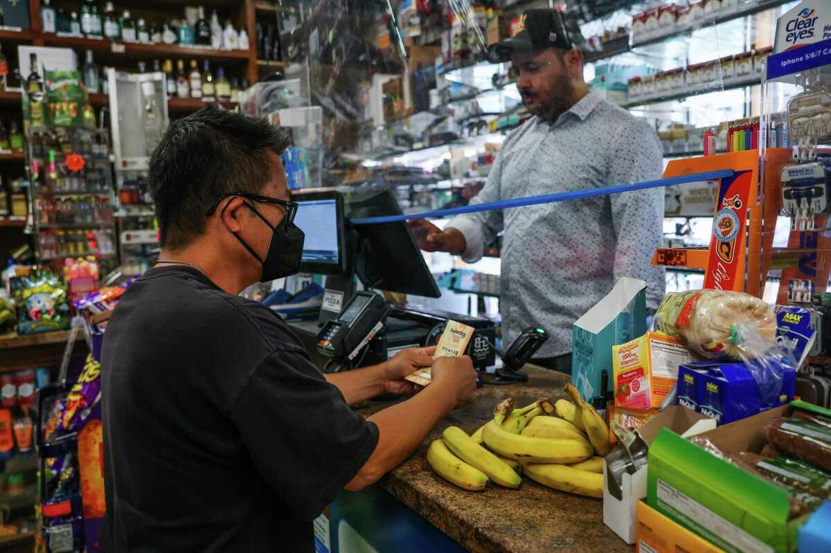 Kevin Leung (left) buys a Mega Millions lotto ticket from Ali Mohamed at W&K Market in San Francisco, Calif., on Wednesday, July 27, 2022.