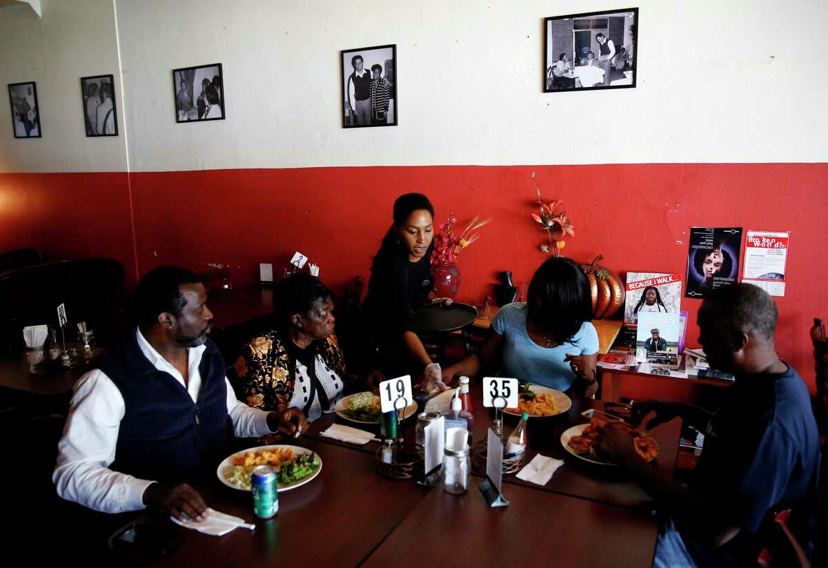 Two Jack’s Nik’s Place owner Nikki Cooper (center) puts a glass of water on the table for customers at her restaurant in San Francisco. The longtime restaurant closed after 45 years.