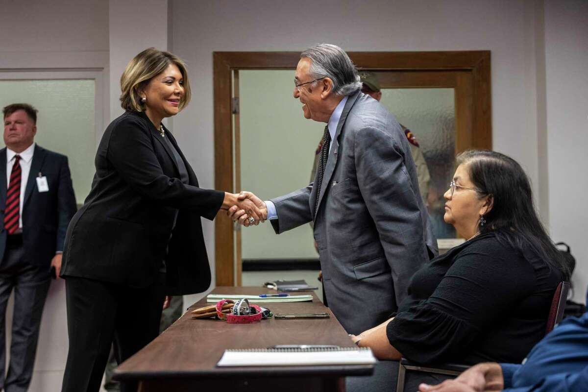 Former Texas Supreme Court Justice Eva Guzman greets Ricardo G. Cedillo, the attorney representing Robb Elementary School Prinicpal Mandy Gutierrez, sitting in foreground, at a June 16 special House committee hearing at Uvalde City Hall on the massacre at the school.