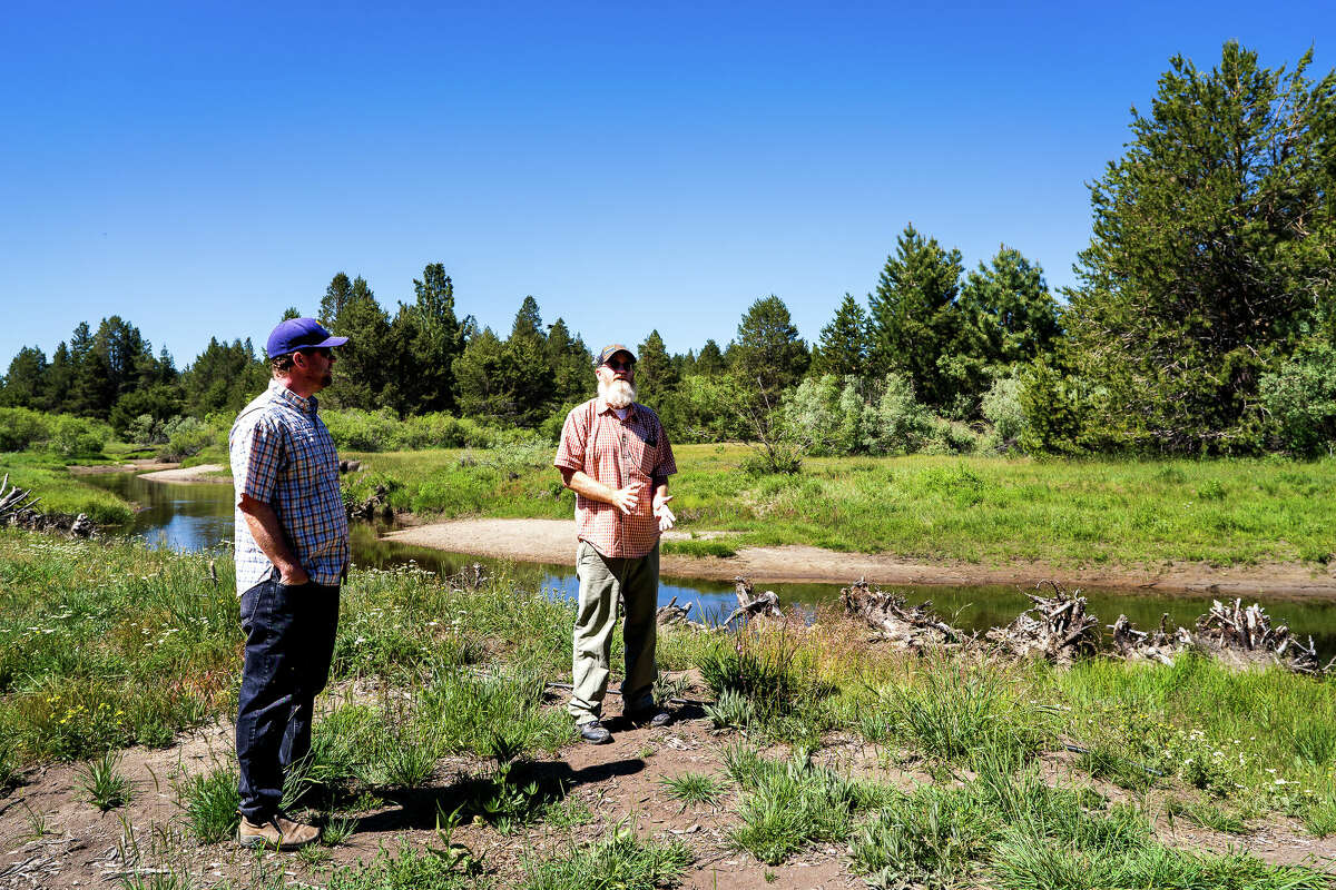 Stuart Roll, left, and Scott Carroll stand next to the Upper Truckee River and surrounding marsh, discussing the science and art of stream restoration.