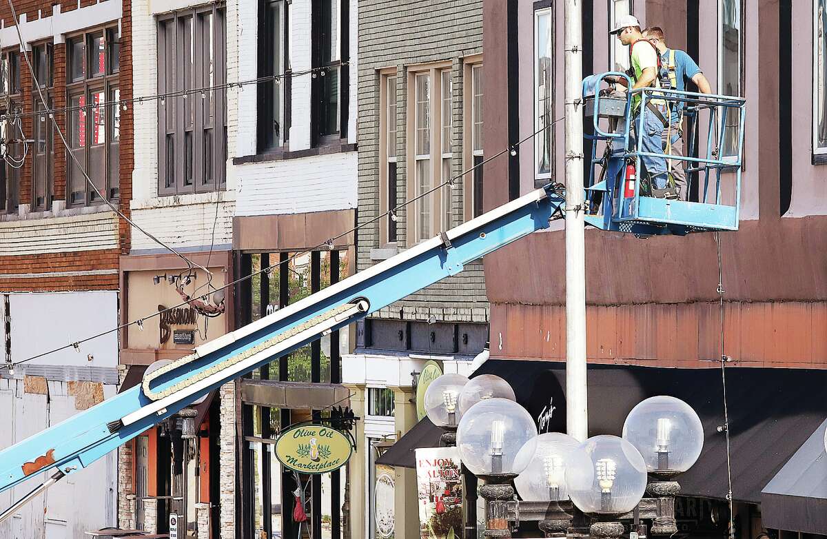 John Badman|The Telegraph Downtown Alton will be getting a bit darker starting this weekend. Workers from GRP Weigman on Friday removed the strands of lights that crisscross 3rd Street between Piasa and State streets. In December 2020 Netflix selected Alton as one of six cities in the country to receive the lights. They were removed this week to make way for construction and re-paving equipment as part of the Illinois American Water sewer separation project in downtown Alton. Workers did not want to chance hitting the lights with heavy equipment as it passed beneath. The strands were collected and coiled up in plastic containers for storage. Worry not; they will be going back up when the construction work has concluded.