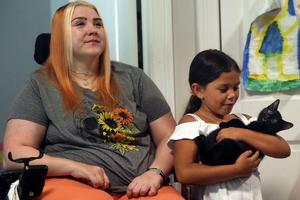 Meghan Nealy sits with her daughter, Aliyah, 6, and their new kitten Tommy during an interview in their home in Shelton, Conn. July 27, 2022. Nealy was seriously injured in motor vehicle crash in Shelton in February 2020 and uses a wheelchair. Two people, including Aliyah’s father, Adrian Joshua Miles, were killed in the crash.
