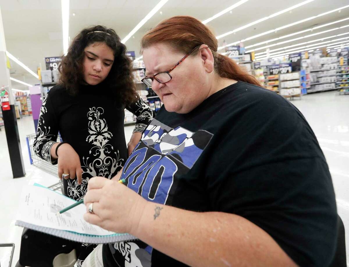 Melvin Morrales, right, looks over a school supply list with her granddaughter, Audrina Morralas, as staff with the Conroe Salvation Army took a group of 12 student on a school supply shopping spree at Walmart, Friday, July 29, 2022, in Conroe. The Salvation Army ladies auxiliary raised $100 for each student to shop for back to school needs.