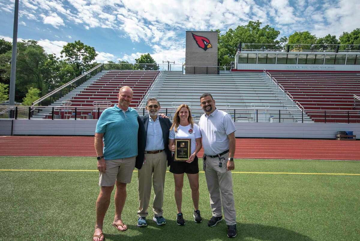 From left, Greenwich Board of Education member and president of Rugby Connecticut Joe Kelly; Greenwich High principal Ralph Mayo; Greenwich girls rugby coach Erin Martschanko; and interim director of athletics Peter Georgiou pose with the 2022 Girls Rugby Coach of the Year plaque at Cardinal Stadium on Tuesday, July 26, 2022.