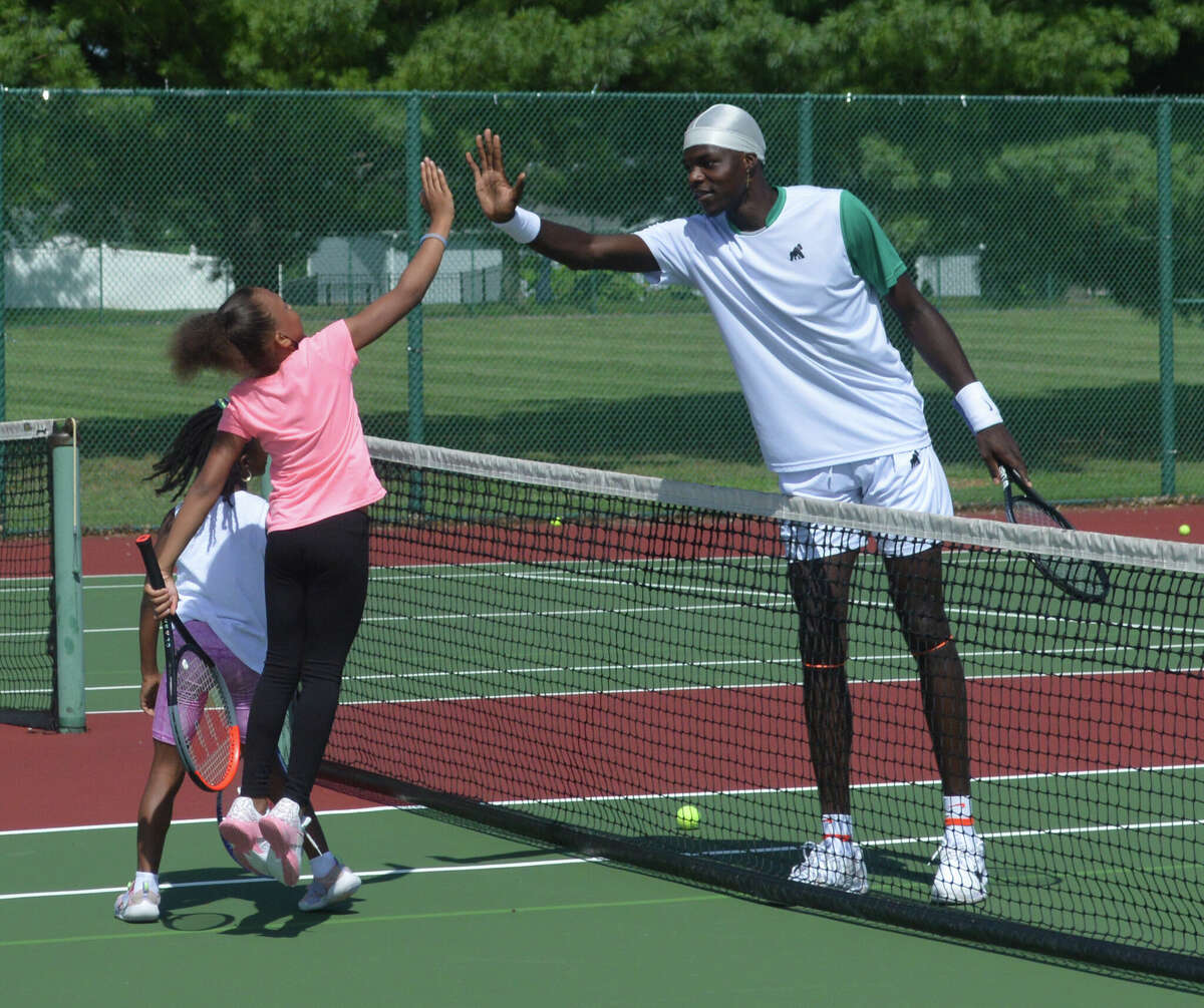 Noell Wheeler high fives former University of Illinois tennis player Kweisi Kenyatte at Diversity Day at the Futures on Friday. 