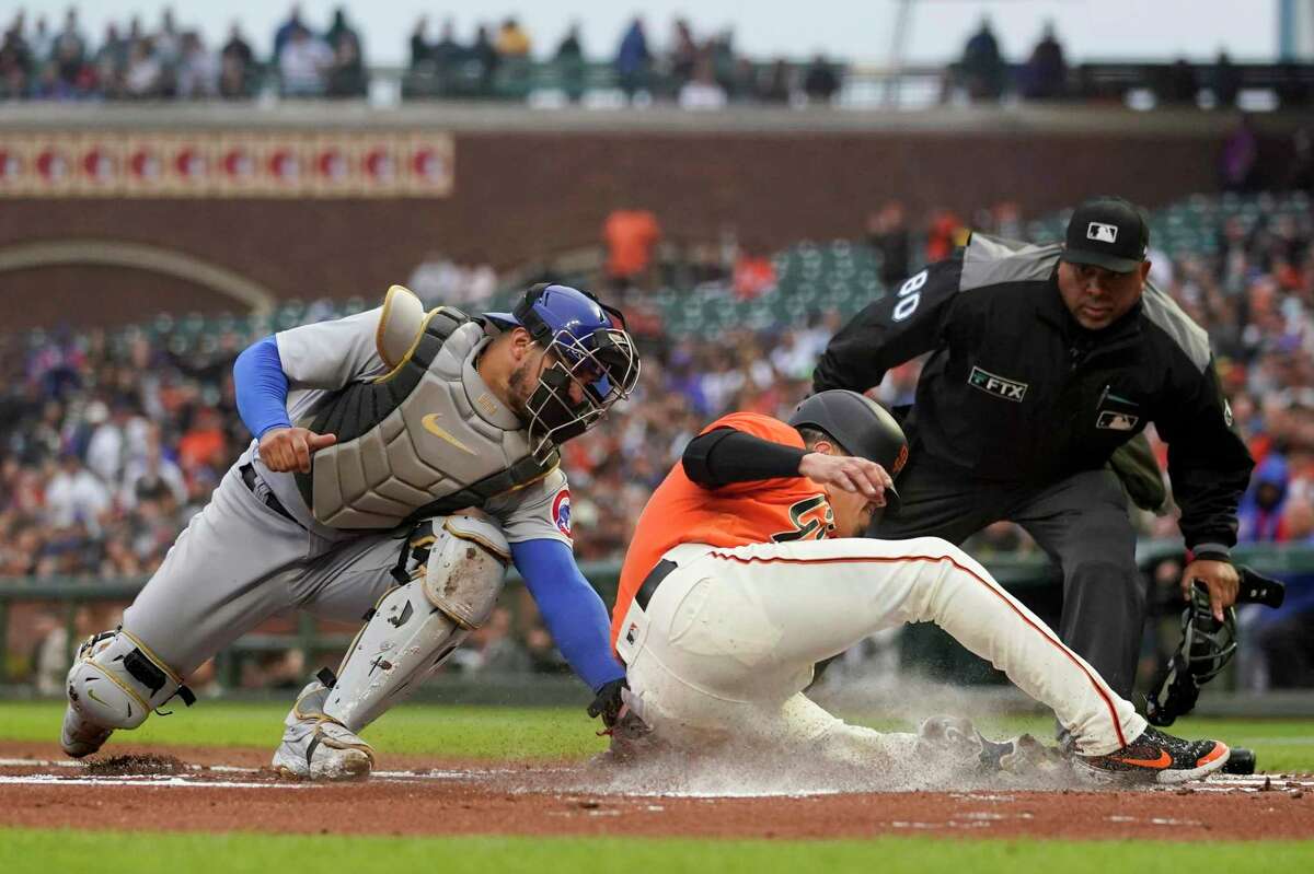 Chicago Cubs catcher Willson Contreras, left, tags out San Francisco Giants' Wilmer Flores during the first inning of a baseball game in San Francisco, Friday, July 29, 2022. (AP Photo/Godofredo A. Vásquez)