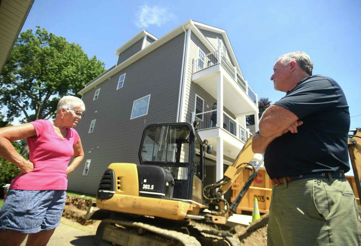 Grant Street residents Sarah Newell, left, and Dennis O'Grady, in front of the four story home being constructed on Grant Street, on an elevated pad of soil, that has raised the ire of neighborhood residents, in Milford, Conn. on Wednesday, July 27, 2022.
