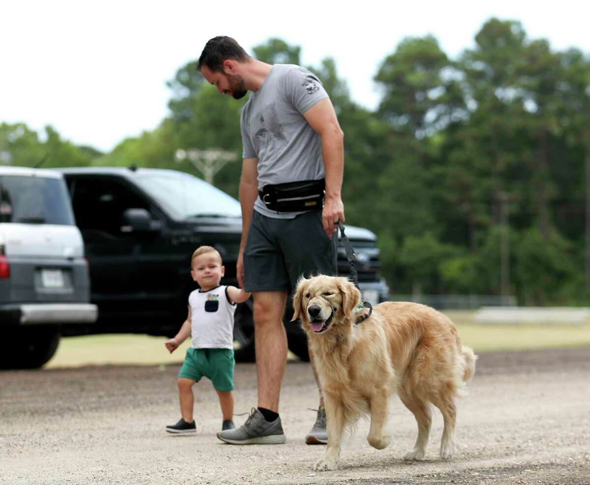 Caleb Newell walks with his son, Banks, and Golden Retriever, Moose, during the inaugural Yap and Splash at Owen Park, Saturday, July 30, 2022, in Conroe.