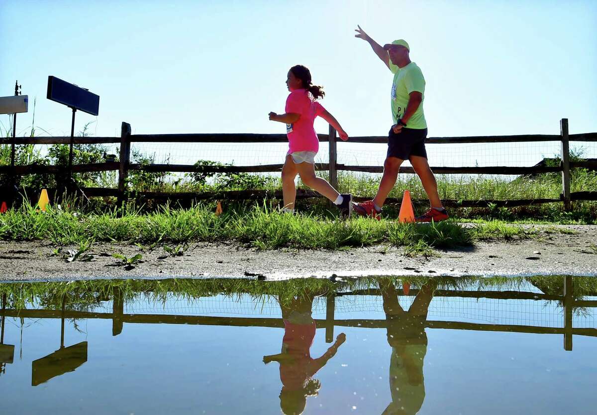 Carlos Lithgow encourages his daughter Mia, 7, to the finish line as they take part in the 1K fun run during the Greenwich Road Runners Race Series: Summer at the Point 5K at Greenwich Point Park in Greenwich, Conn., on Saturday July 30, 2022.