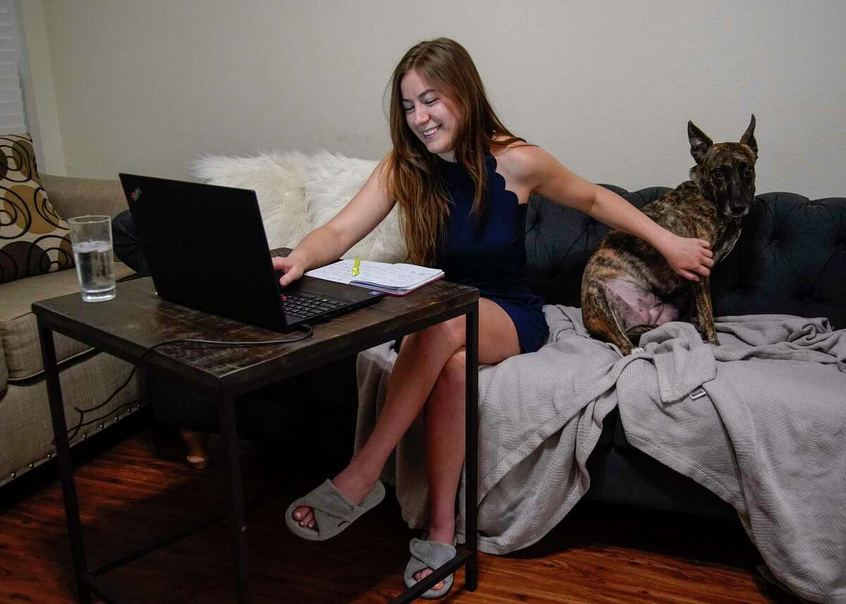 Abigail Schwaig works on her computer with her rescue Shepherd/Plotthound, Jewel, at her side at her apartment on Friday, July 15, 2022 in Houston. Schwaig, a 28-year-old Houston native who recently changed jobs to work for a large engineering firm and priortized flexibility in her job search.