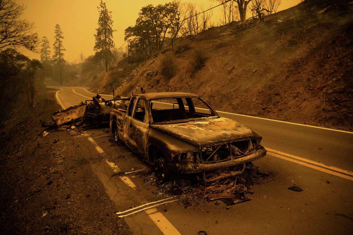 一辆烧焦的皮卡停在克拉马斯国家森林的加州96号高速公路上，麦金尼大火在附近燃烧。