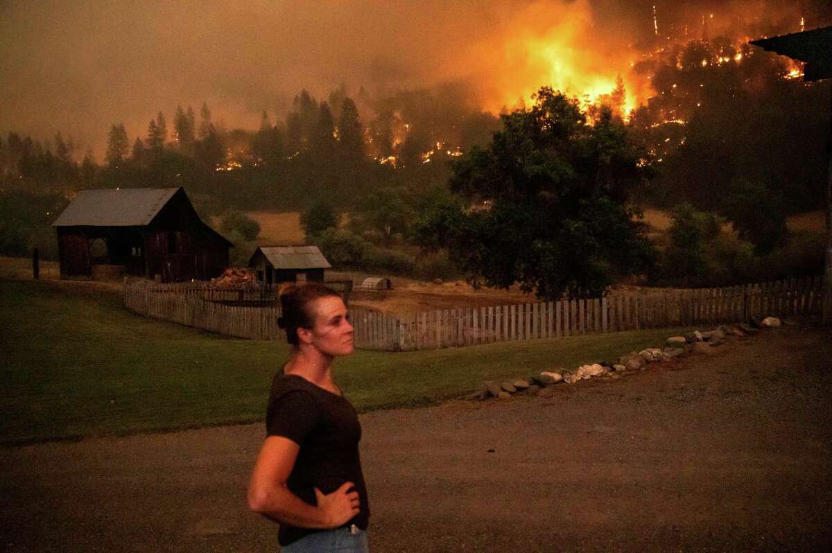 Angela Crawford kijkt toe hoe een bosbrand, de McKinney-brand genaamd, op zaterdag 30 juli 2022 een heuvel boven haar huis in Klamath National Forest, Californië, verbrandt. Crawford en haar man bleven, terwijl andere bewoners evacueerden, om hun huis tegen het vuur te verdedigen .