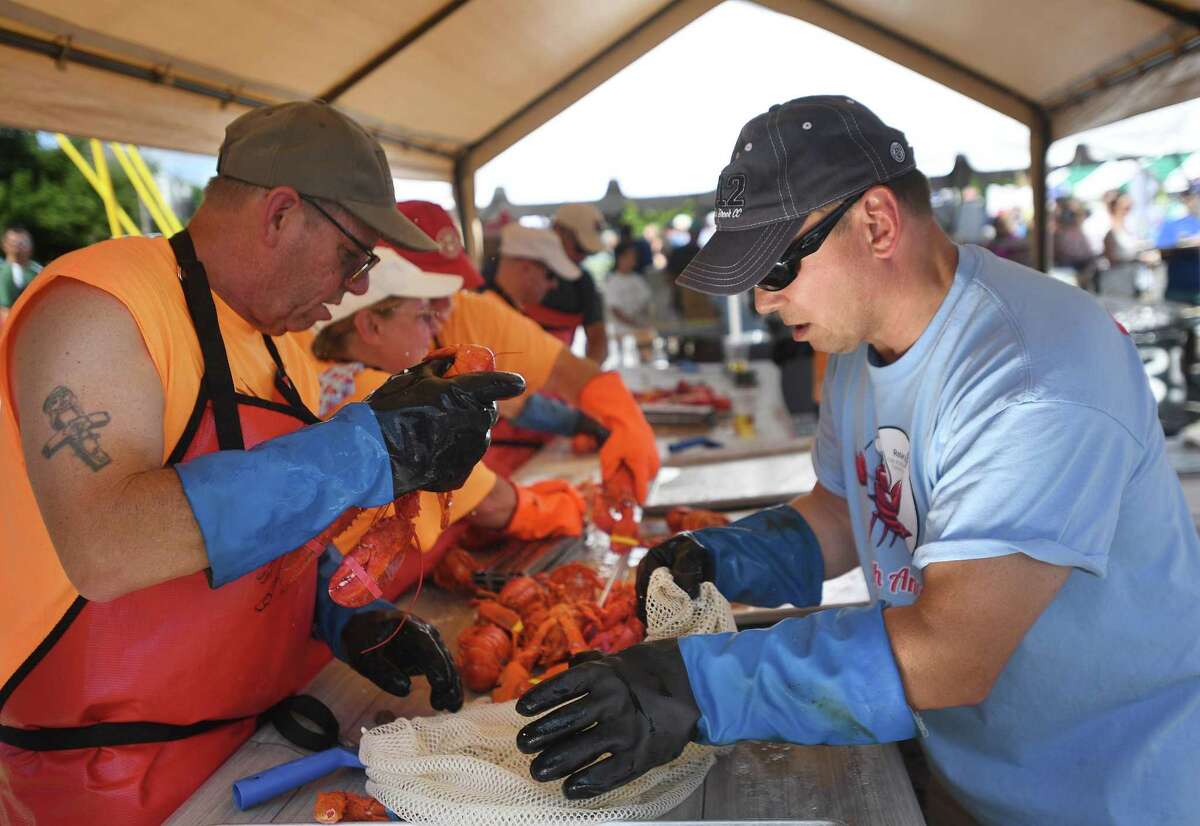 Rotary members Mark Sandillo, left, and Dave Piechot empty bags of cooked lobsters at the annual Milford Lobster Bake at Lisman Landing in Milford, Conn. on Saturday, July 30, 2022.