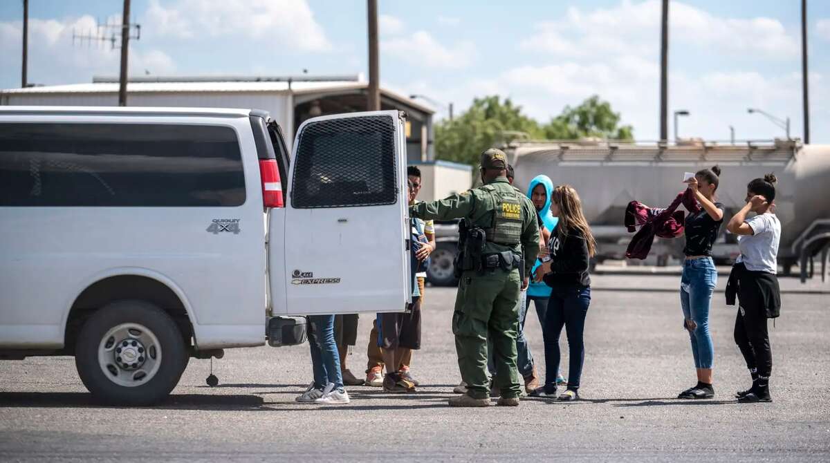 People who were apprehended by state troopers after crossing the border are brought to the International Bridge in Eagle Pass on May 28 to be handed over to Border Patrol custody. 