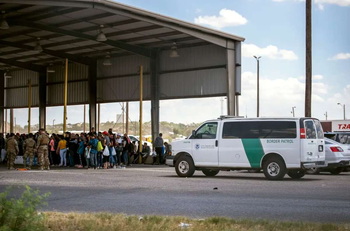 People who were apprehended by state troopers after crossing the border are brought to the International Bridge in Eagle Pass on May 28 to be handed over to Border Patrol custody.