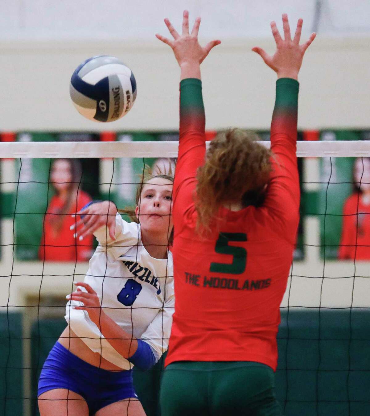Grand Oaks’ Caelyn Emmerling (8) gets a shot past The Woodlands’ Ella Lewis (5) during the first set of a high school volleyball match at The Woodlands High School, Tuesday, Sept. 28, 2021, in The Woodlands.
