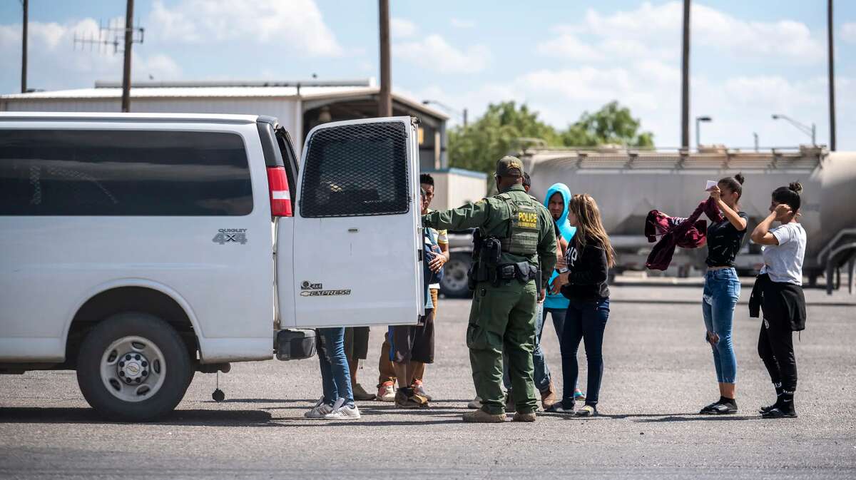 People who were apprehended by state troopers after crossing the border are brought to the International Bridge in Eagle Pass on May 28 to be handed over to Border Patrol custody.