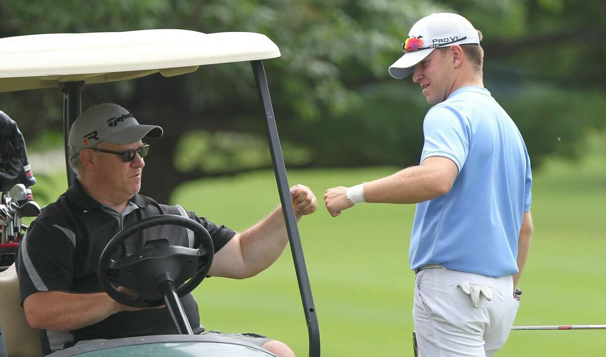 Brady Kaufmann gives his dad a fist-bump as he walks off the 18th green on the final day of the Jacksonville City Golf Tournament on Sunday.